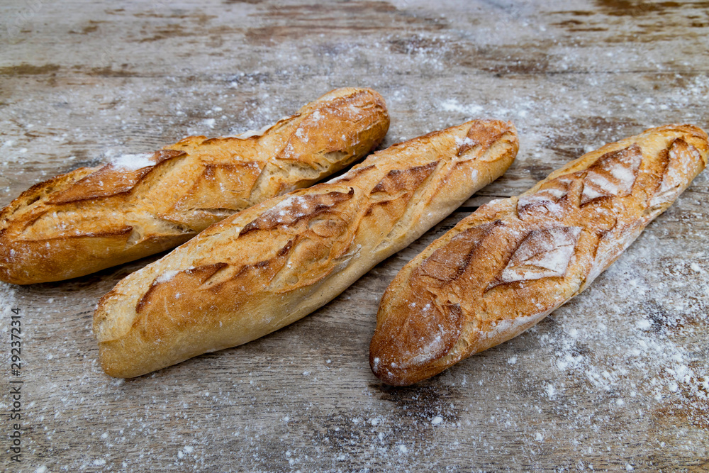 .Three fresh crunchy french baguettes on a wooden background.