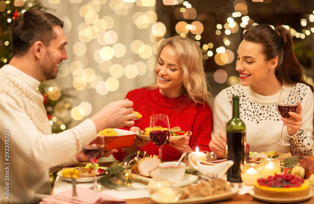 holidays and celebration concept - happy friends having christmas dinner at home, eating and drinking holidays and celebration concept - happy friends having christmas dinner at home, eating and drinking