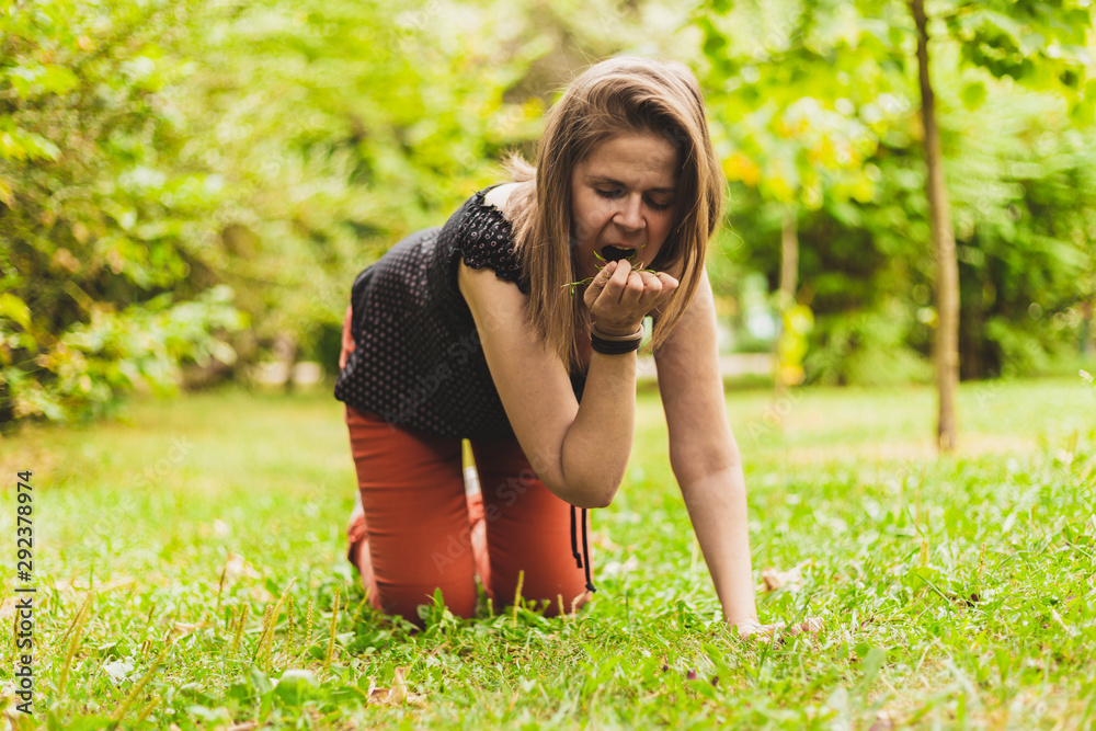 Fototapeta premium Young woman grazing fresh green grass in the park