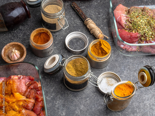 Obraz na płótnie different pickled meat in glass bowls, and jars with spices ad herbs as curcuma,cardamon, rosemary, black pepper, soy and pomegranate sauce on grey background w salonie