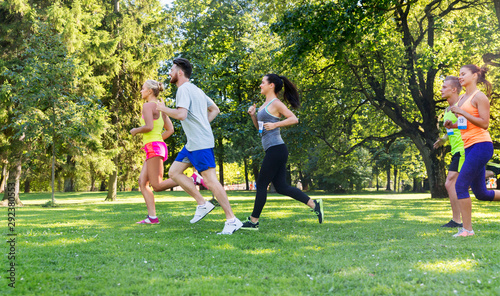 fitness, sport, race and healthy lifestyle concept - group of happy people or sportsmen running marathon with badge numbers at summer park