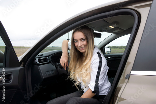 Young, cute and beautiful blonde near a stylish car.