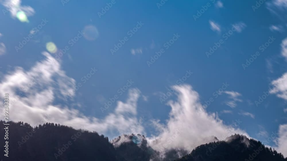 Fast-moving clouds gradually cover the blue sky over a mountain range Fast-moving clouds gradually cover the blue sky over a mountain range
