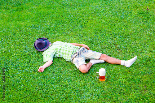 drunken bavarian men sleeps in the meadow