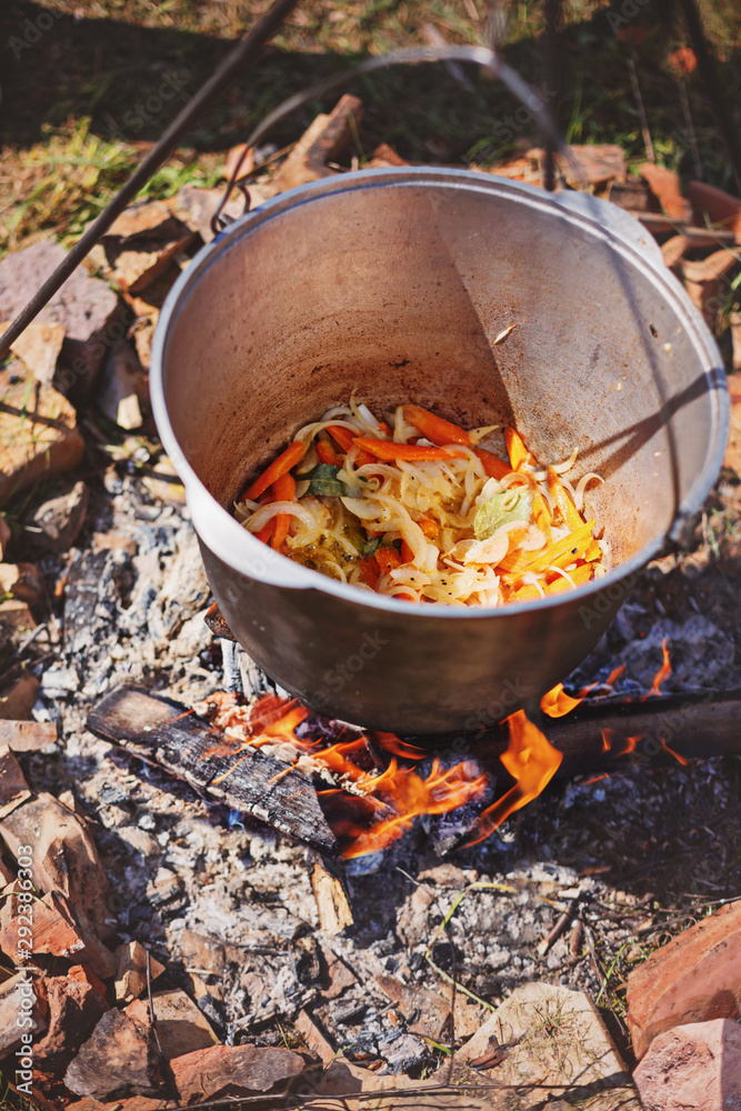 Cooking outdoors in cast iron cauldron on a campfire Cooking outdoors in cast iron cauldron on a campfire