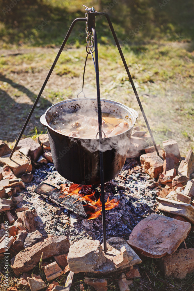 Cooking outdoors in cast iron cauldron on a campfire Cooking outdoors in cast iron cauldron on a campfire