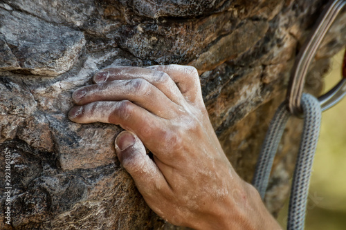 Closeup view of rock climber's hand gripping hold on natural cliff