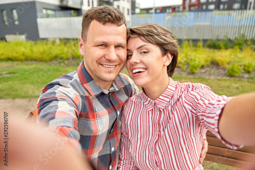 love, valentines day and relationships concept - happy couple in summer park taking selfie outdoors