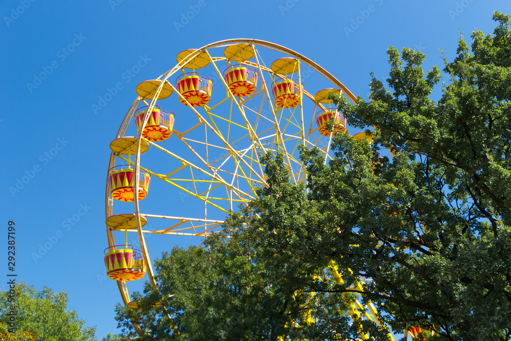 Fototapeta premium Ferris Wheel against blue sky background on sea promenade. Attractions and entertainment during the holidays. Vacation concept.