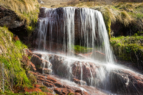 Cascades of powerful Monk's jump waterfall, the tallest in Serbia, streaming down the wet, red cliff rocks during early spring