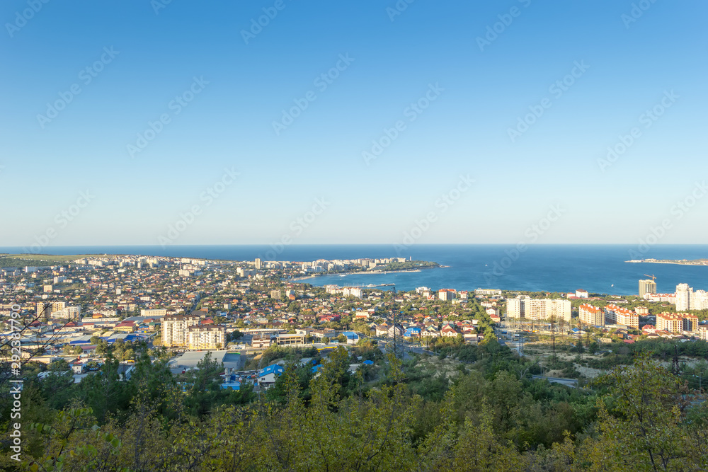Scenic view of Gelendzhik city and sea bay. Sunrise time. Trees on hills on foreground. Vacation on resort.