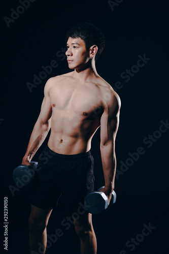 athletic muscular bodybuilder man with naked torso six pack abs working out with dumbbell. fitness  exercise concept