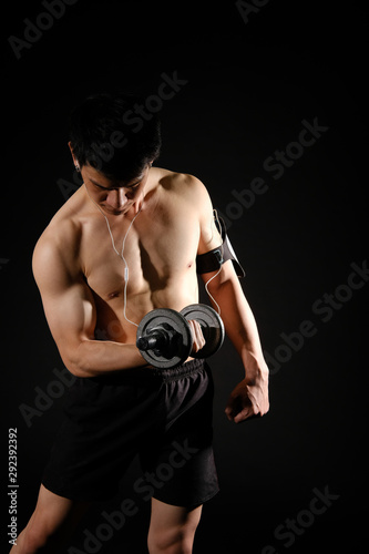 athletic muscular bodybuilder man with smart mobile phone armband working out with dumbbell. fitness workout concept