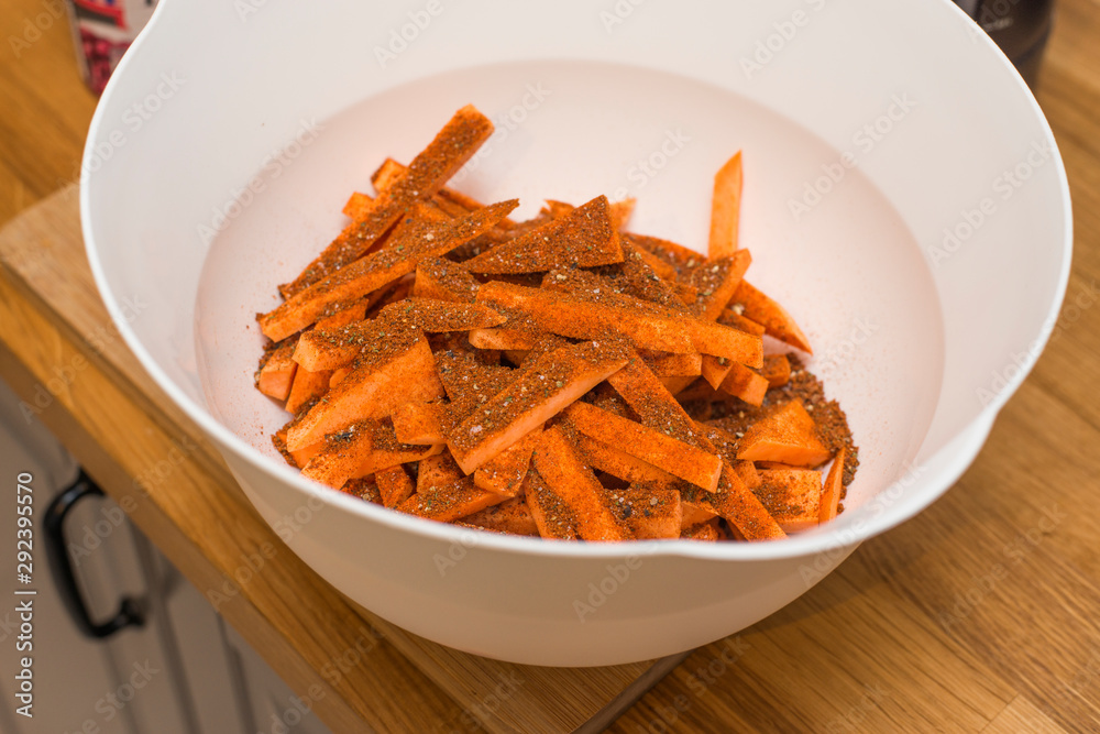 Würzen von Süßkartoffel Pommes in einer Schüssel Würzen von Süßkartoffel Pommes in einer Schüssel