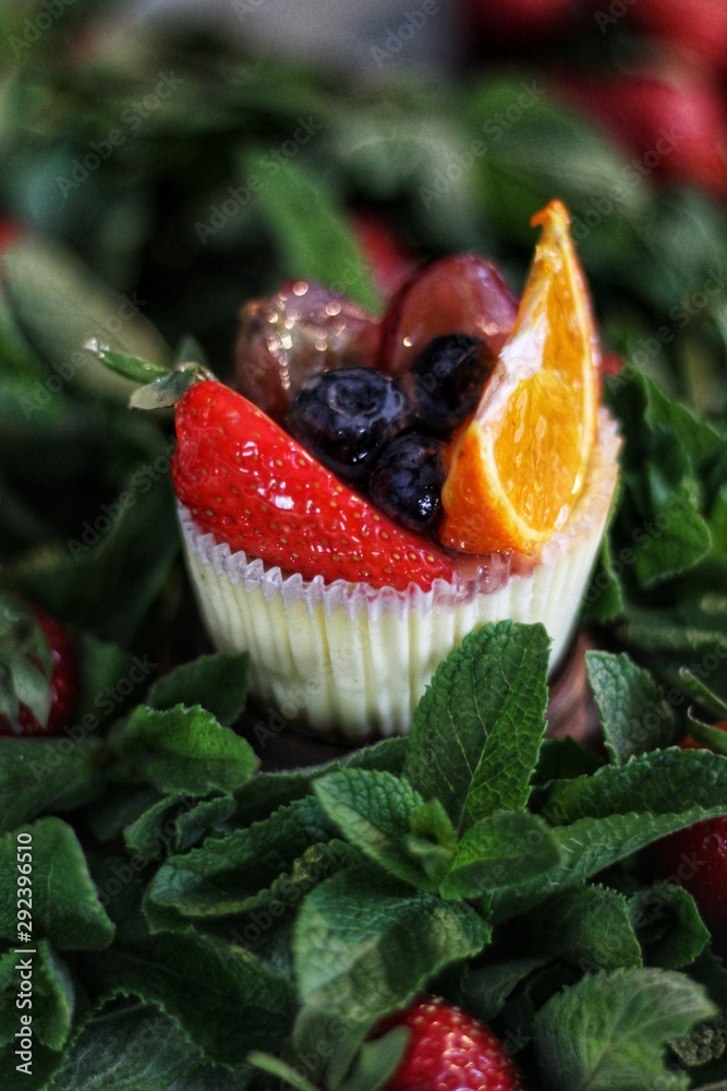 Strawberry cupcake and green leaves on wooden background