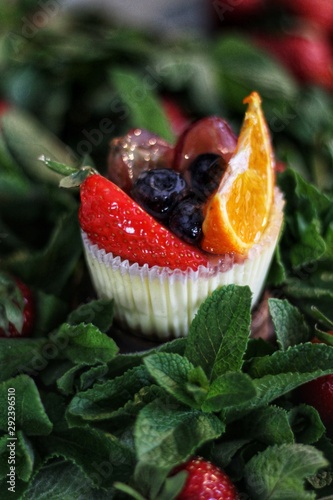 Obraz na płótnie Strawberry cupcake and green leaves on wooden background w salonie