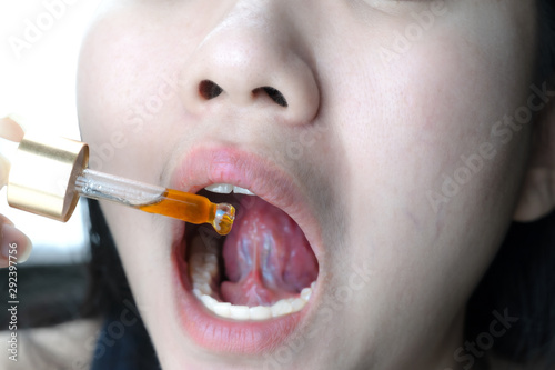 Close up young Asia woman holding a dropper sublingual Cannabis oil Dosing photo