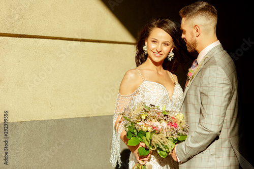 Caucasian romantic young couple celebrating their marriage in city. Tender bride and groom on modern city's street at summersday. Family, relationship, love concept. Contemporary wedding. photo