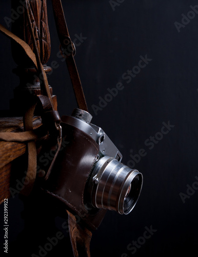Old photo camera with old-fashioned chair in dark key close up
