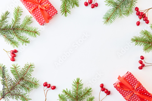 Flat lay frame with evergreen tree branch  berries and gift box on a white background