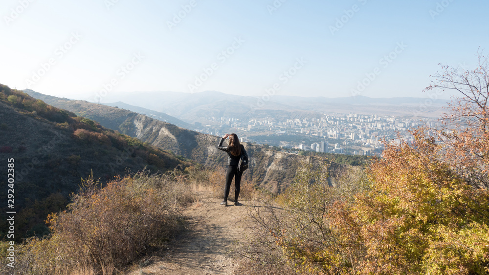 Girl hikes in the mountains on a warm autumn day.