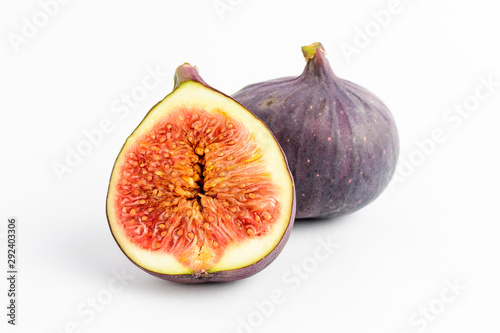 Fresh ripe organic figs on a white table, one whole fig and one sectioned in half, close up with soft focus, top view