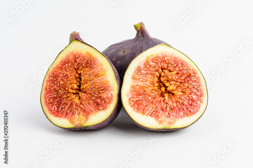 Fresh ripe organic figs on a white table, one whole fig and one sectioned in half, close up with soft focus, top view