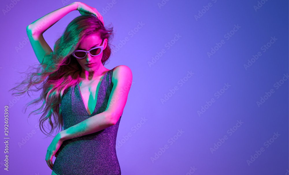High Fashion. Party girl with pink neon hairstyle dance. Young shapely  woman in Colorful uv Light. Pop Art bright fashionable creative Style.  Night Club vibes. Sexy model dancing, neon purple color Stock