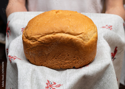 Cook baked fresh wheat bread, holding in his hands on a linen towel