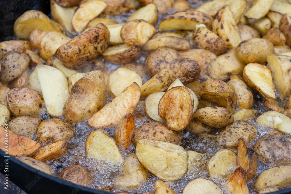Roast potatoes in a large pan.Young potatoes are fried in oil, street food Roast potatoes in a large pan.Young potatoes are fried in oil, street food
