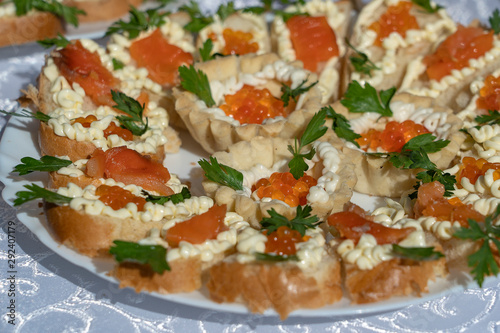 Set of delicious tartlets with red caviar, closeup. Many tartlets with butter and red caviar on a plate