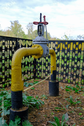 The pipeline with a valve leaves the ground in the forest belt.