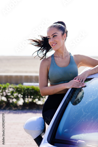 Portrait of happy young woman going on a road trip leaning out of window with Hair In Wind. © Miri García
