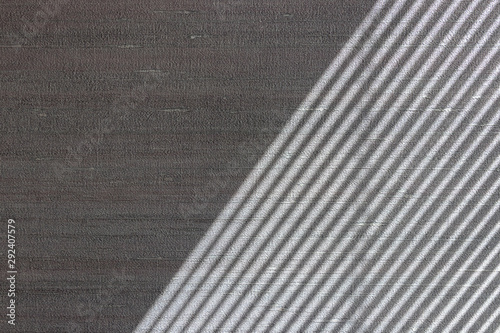 Hard diagonal shadows on grey textured wall from a window roller shutter or blinds. Attractive abstract half frame composition photo