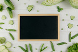 Food photography. Green vegetables around a blackboard on a white background.