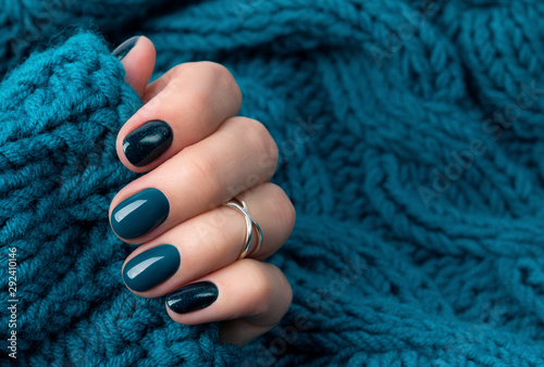 Manicured woman's hand in warm wool turquoise sweater