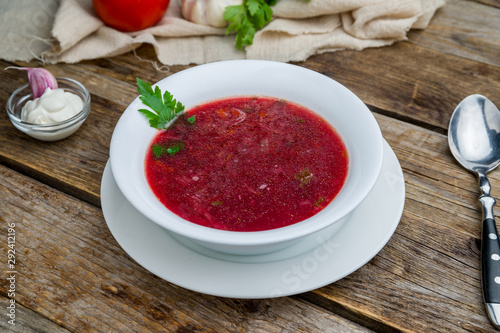 Borscht with sour cream on wooden table