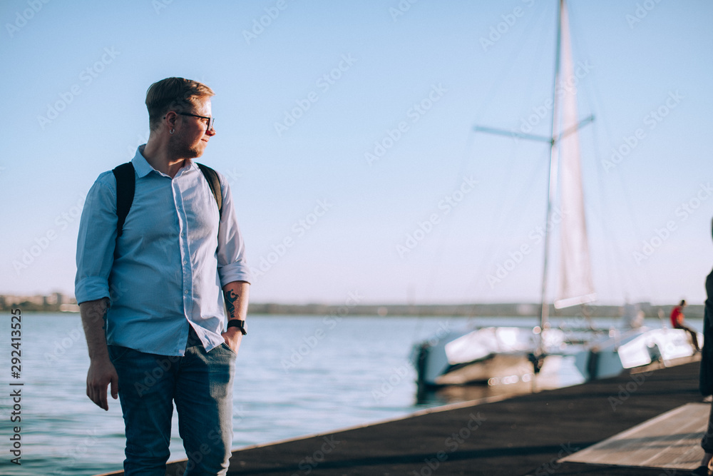 A young man stands by the lake at sunset. A young man stands by the lake at sunset.