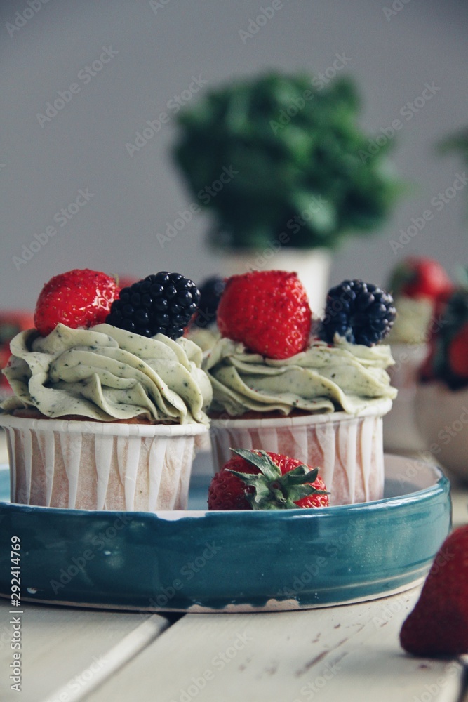Strawberry cupcakes and green leaves on wooden background