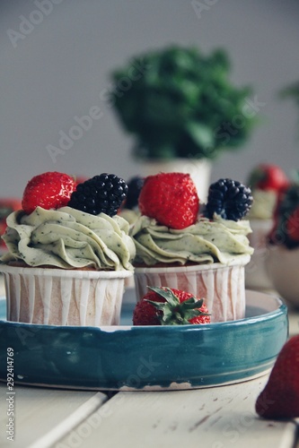 Obraz na płótnie Strawberry cupcakes and green leaves on wooden background w salonie