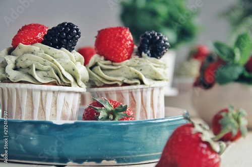 Obraz na płótnie Strawberry cupcakes and green leaves on wooden background w salonie