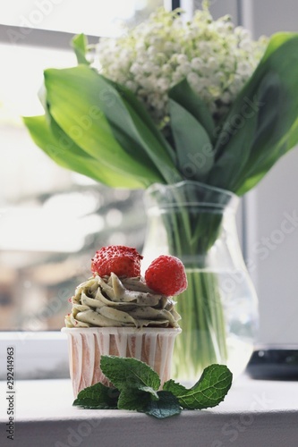 Strawberry cupcake and green leaves on wooden background