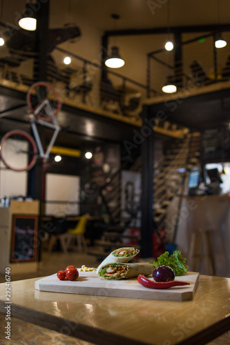 Appetizing fast food on a wooden board with fresh vegetables.