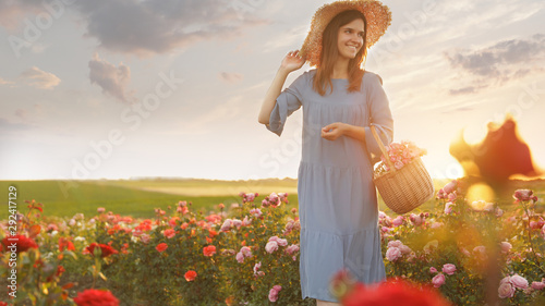 Fototapeta Naklejka Na Ścianę i Meble -  Woman with basket of roses in beautiful blooming field