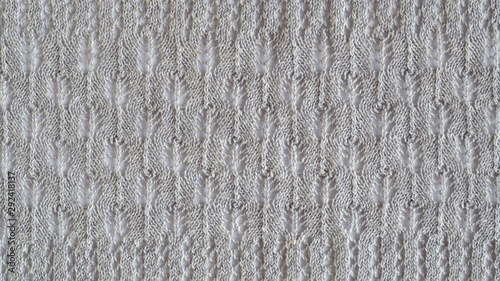 Lace stitch pattern with leaves on white backround. Neutral gray color knitted texture. Closeup