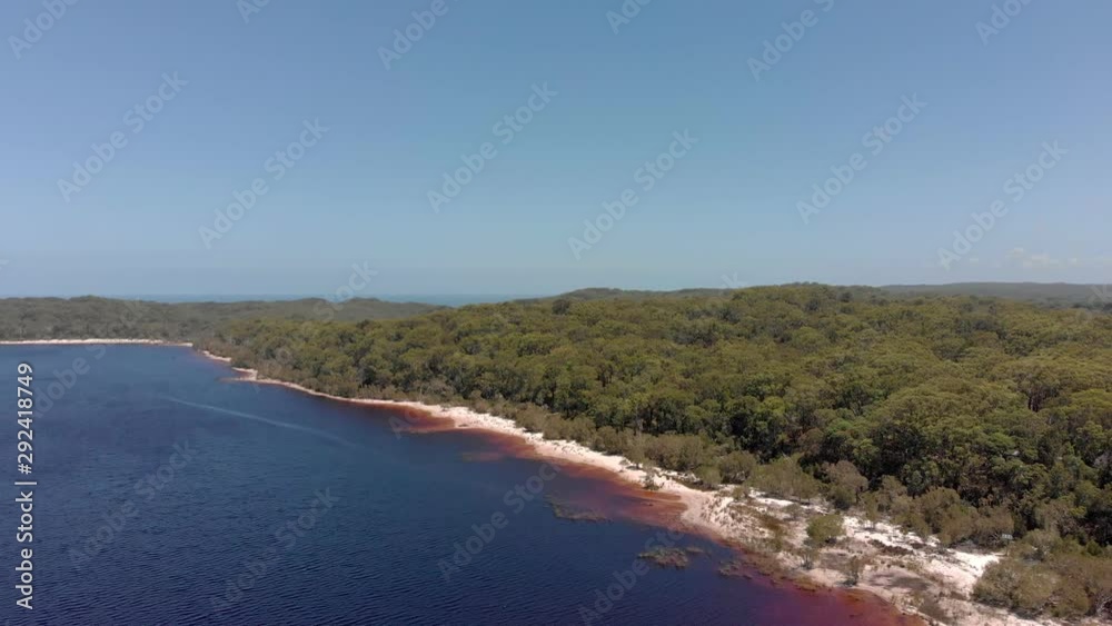 Fraser Island, Lake Boomanjin. Aerial view pull back above Australian sandy woodland shoreline Fraser Island, Lake Boomanjin. Aerial view pull back above Australian sandy woodland shoreline