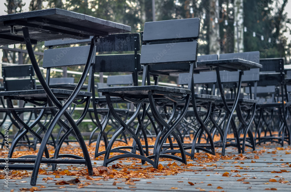 Wooden floor of street cafe covered with orange autumn leaves. Selective focus.