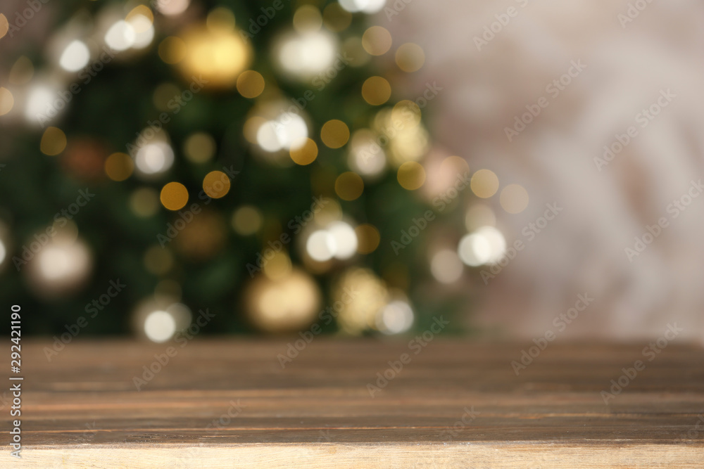 Empty wooden table and blurred fir tree with Christmas lights on background, bokeh effect. Space for design
