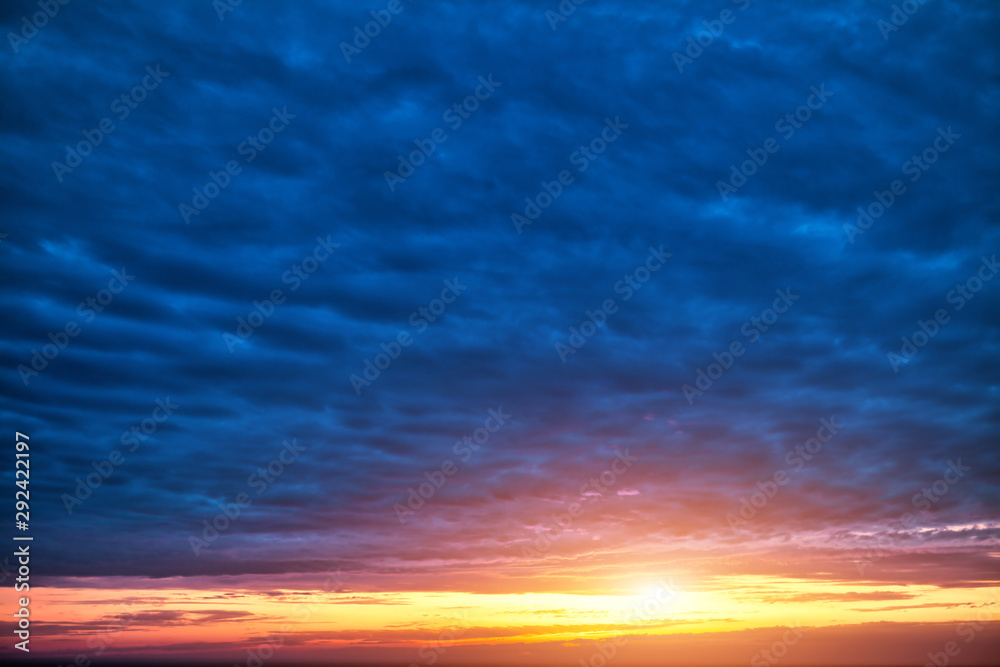 Sunset on the horizon. Cloudy dark blue sky and golden sundown.