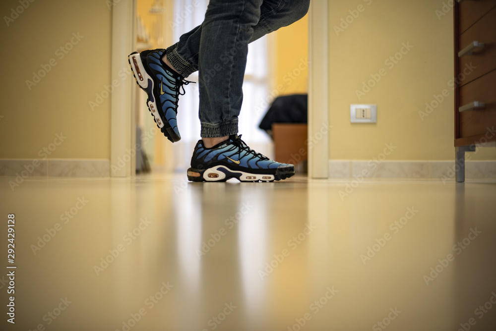 Young man wearing Nike Air Max Plus TN Hyperblue shoes at home Stock Photo  | Adobe Stock